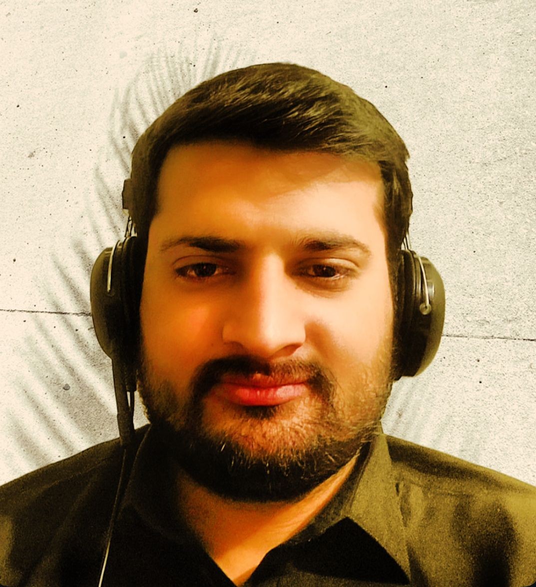 Man with headphones against a textured wall, casting shadow patterns.
